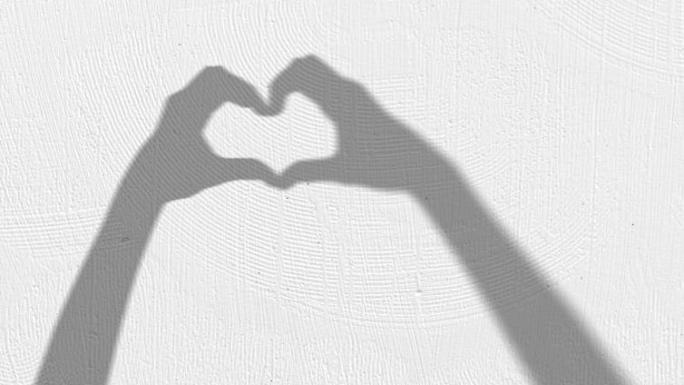 Two hands making the shape of a heart in a shadow